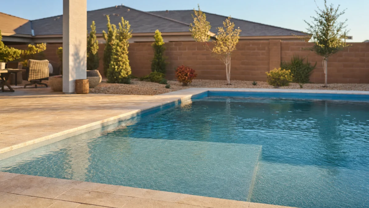 Newly finished fiberglass pool with a shallow tanning ledge in a compact backyard