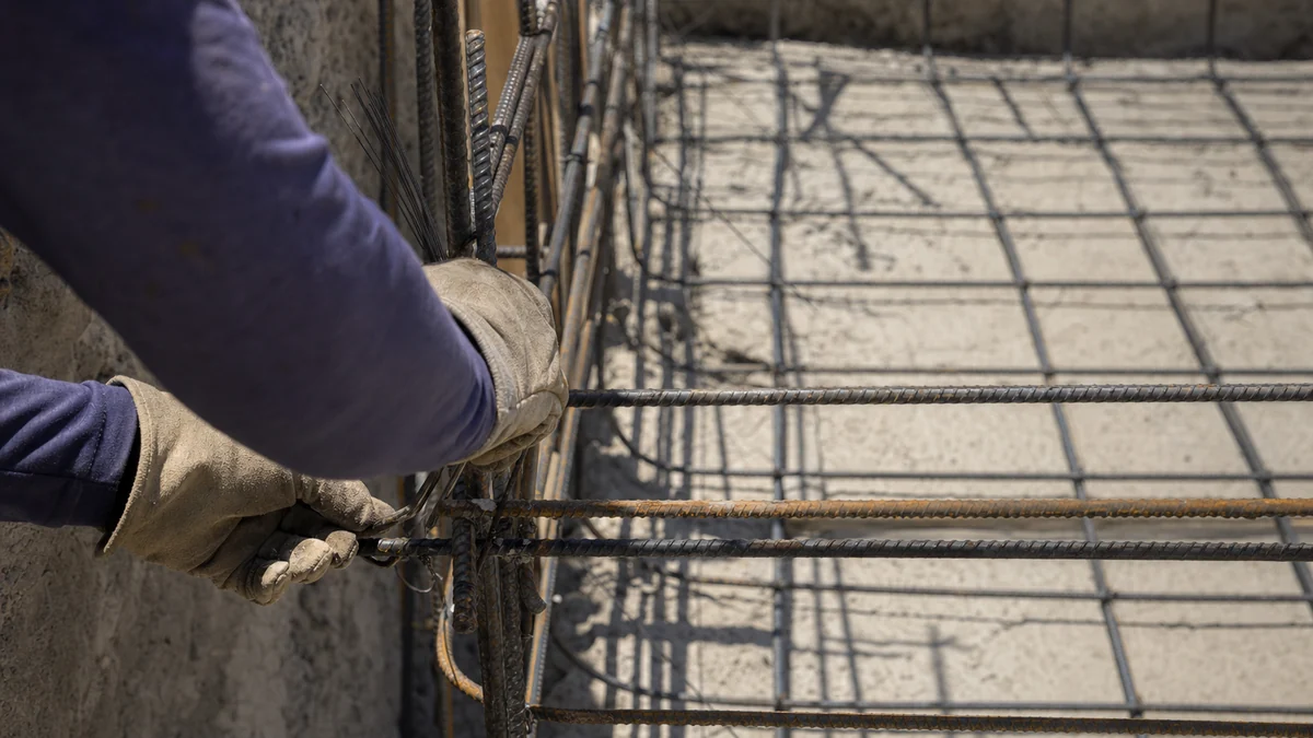 Pool construction crew tying steel rebar inside an excavated pool shell