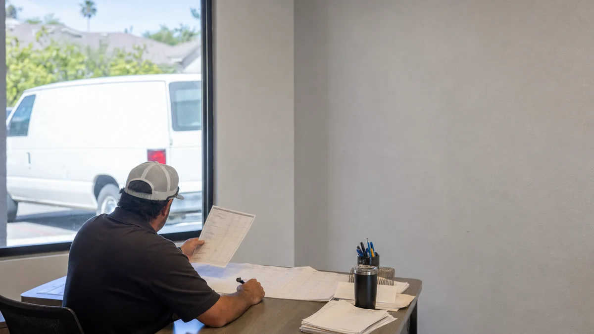Restoration company owner reviewing the crew schedule and job list in a small office